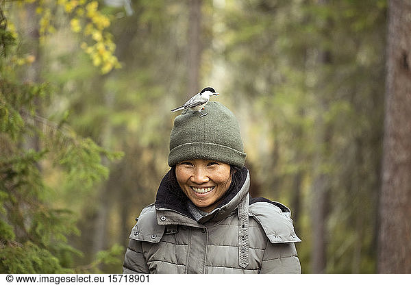 Portrait of woman with willow tit  Poecile montanus  on her hat