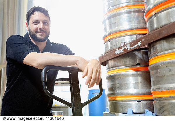 Portrait of worker in brewery organising beer barrels for delivery