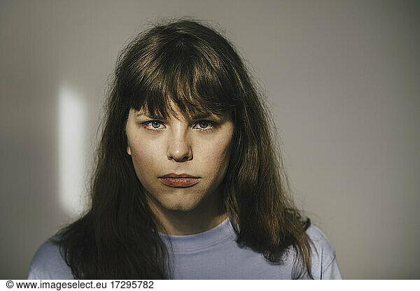 Portrait of young angry woman against white wall