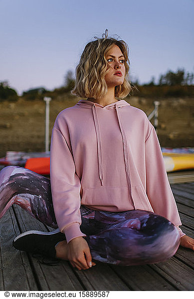 Portrait of young blond woman wearing pink hoodie sweater on jetty