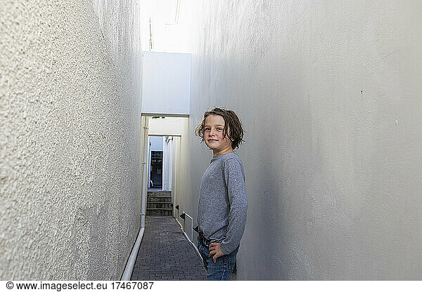 Portrait of young boy in a narrow alleyway  turning to look at the camera