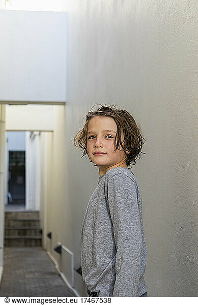 Portrait of young boy in a narrow alleyway  turning to look at the camera