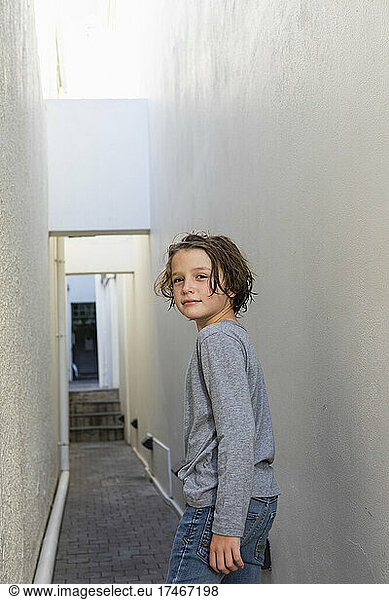 Portrait of young boy in alleyway  turning around to look at the camera.