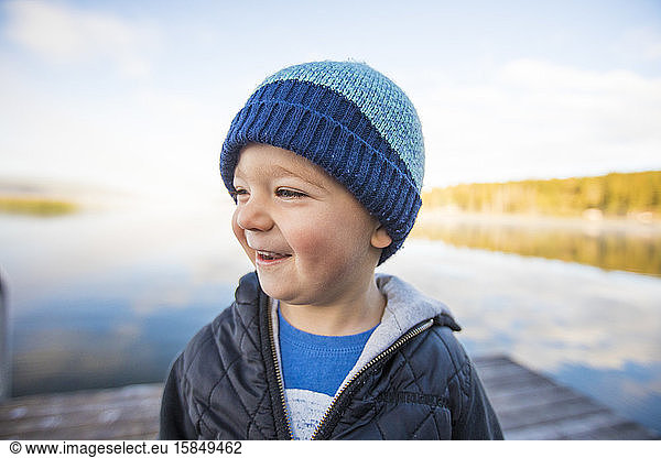 Portrait of young boy laughing on dock.
