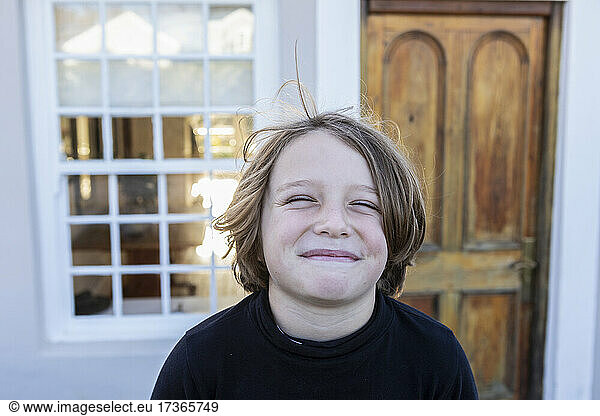 Portrait of young boy posing outside his home  smiling