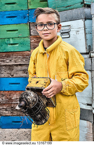 Portrait of young boy wearing beekeeper dress holding a bee smoker