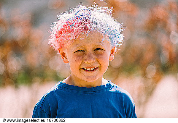 Portrait of young boy with colored hair smiling at camera