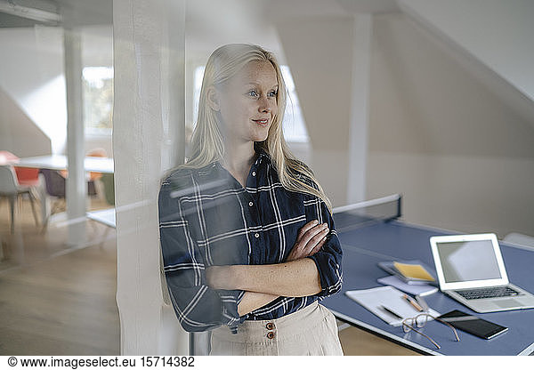 Portrait of young businesswoman in office with table tennis table