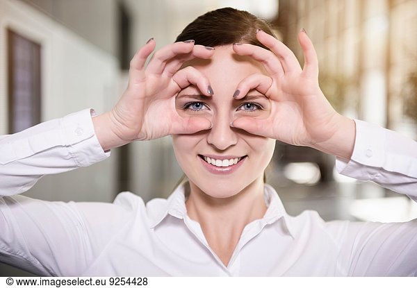 Portrait of young businesswoman making face with hand spectacles