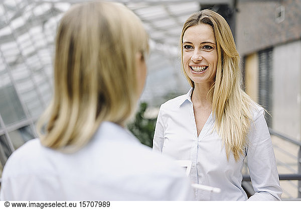 Portrait of young businesswoman smiling at colleague in office