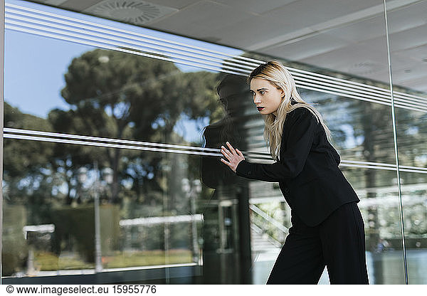 Portrait of young businesswoman wearing black pantsuit standing in front of glass pane