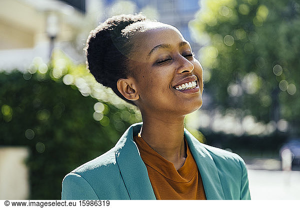 Portrait of young businesswoman with eyes closed outdoors