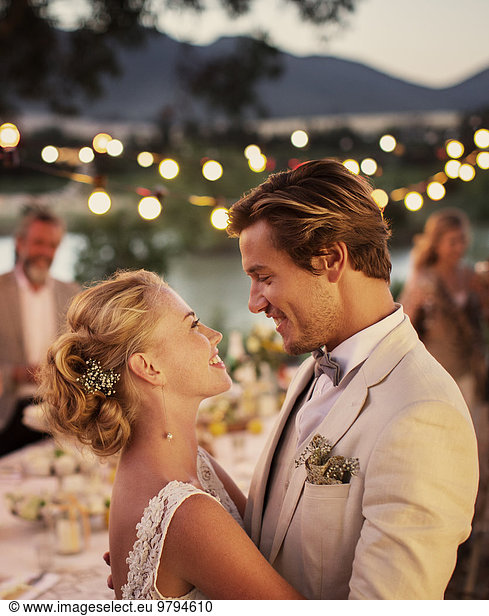 Portrait of young couple dancing in garden during wedding reception