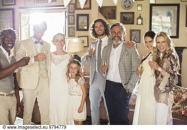 Portrait of young couple with guests and champagne flutes at wedding reception