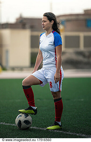 portrait of young female soccer player steps on the ball on the field