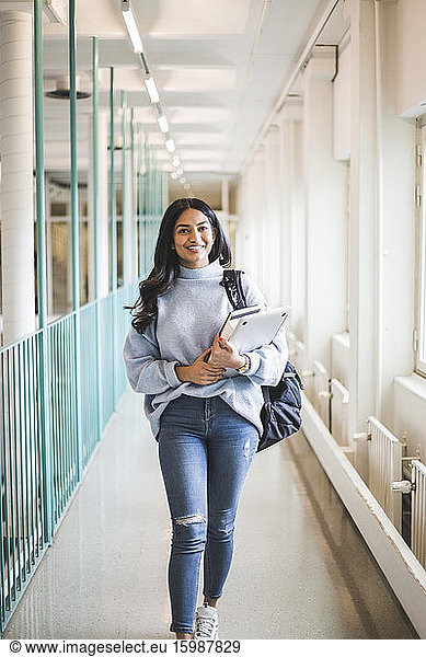 Portrait of young female student walking in corridor of university