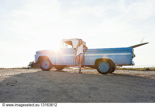 Portrait of young female surfer leaning against pickup truck at beach  Encinitas  California  USA