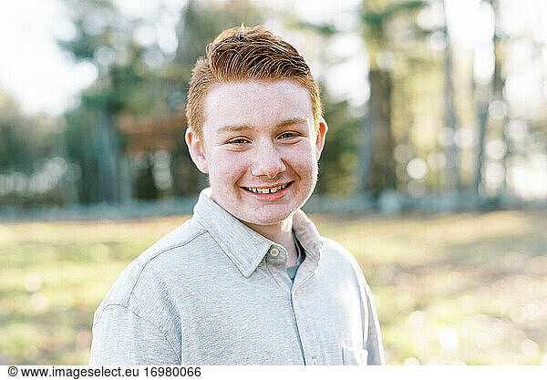 portrait of young ginger boy with blue eyes and freckles smiling