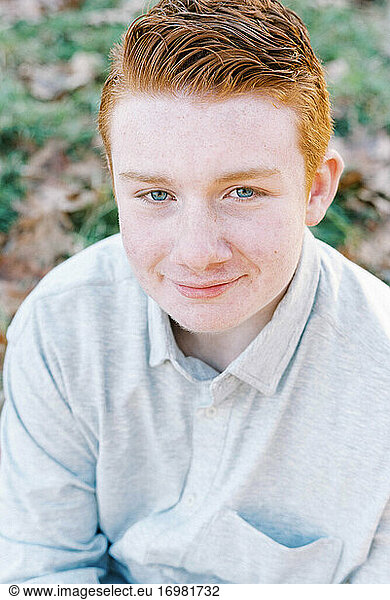 portrait of young ginger boy with blue eyes and freckles smiling