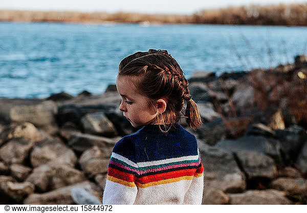 portrait of young girl looking away on rocks at a lake