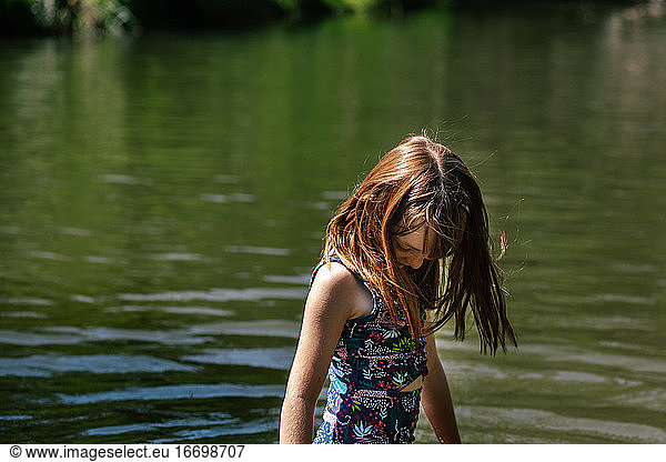 Portrait of young girl standing in a river on a sunny summer day