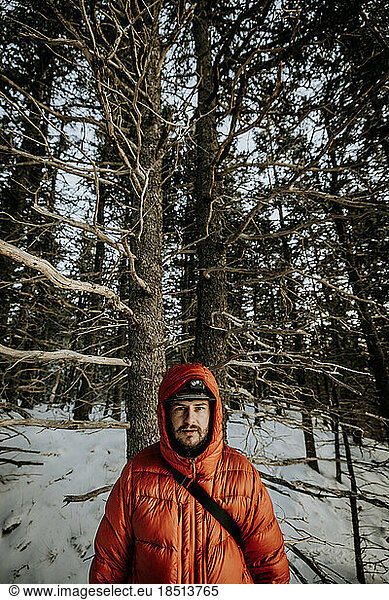 Portrait of young man in winter wearing orange puffy jacket with hood.