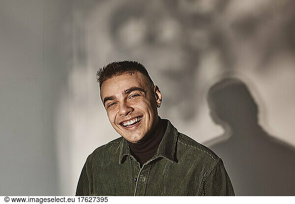 Portrait of young man laughing against white background