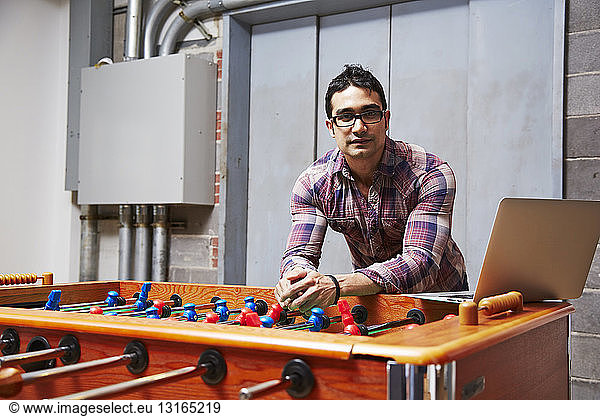 Portrait of young man leaning on table football