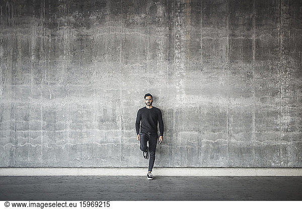 Portrait of young man standing against gray wall