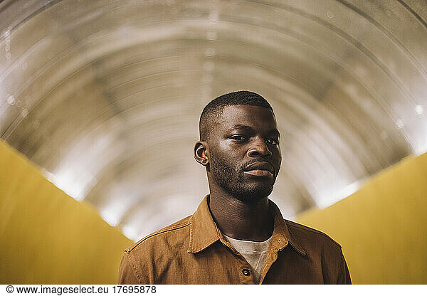 Portrait of young man standing in subway tunnel