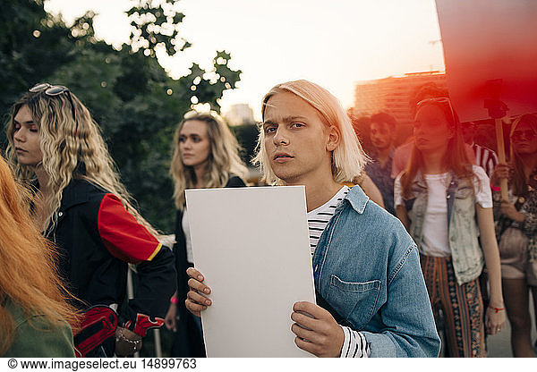Portrait of young man with friends protesting in city
