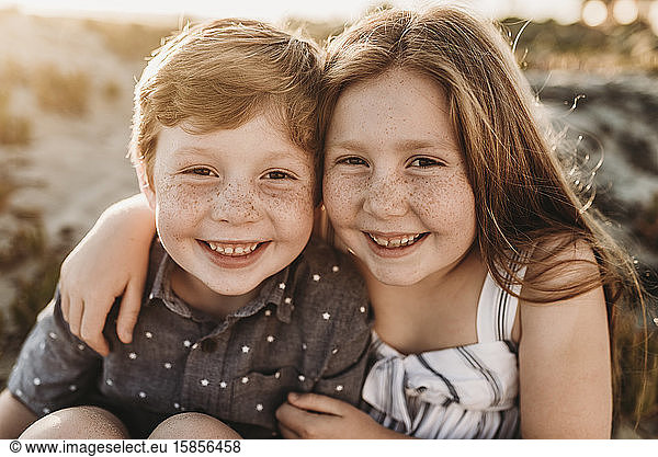 Portrait of young redheaded freckled siblings smiling during sunset