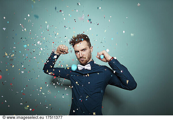 Portrait of young serious man throwing confetti