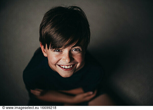 Portrait of young smiling boy with freckles shot from above.