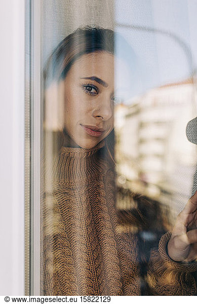Portrait of young woman behind windowpane