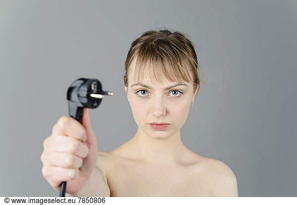 Portrait of young woman holding power plug  close up