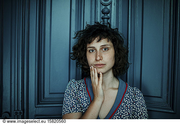 Portrait of young woman in front of blue wooden door