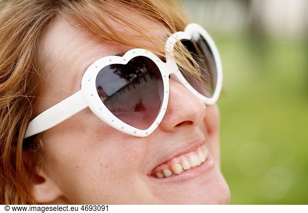Portrait of young woman outdoors with heart-shaped sunglasses