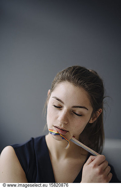 Portrait of young woman pulling off sticky tape from her mouth