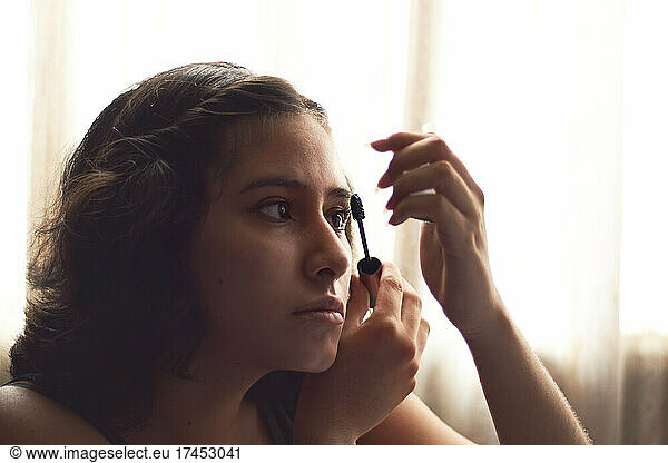 Portrait of young woman putting on makeup  with sun behind