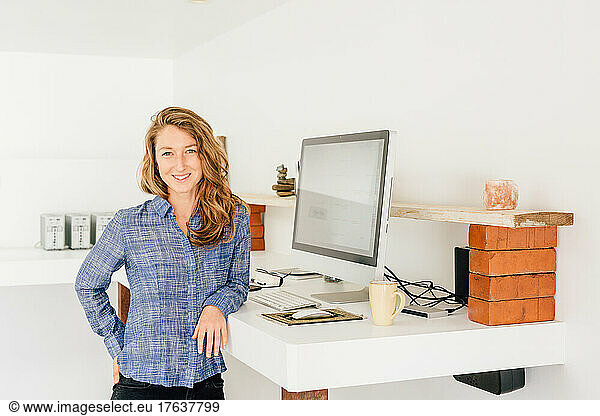 Portrait of young woman standing at work desk
