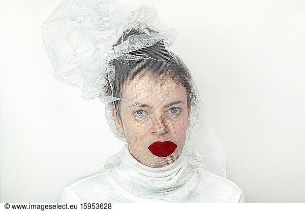 Portrait of young woman wearing transparent tulle mask with red fake lips
