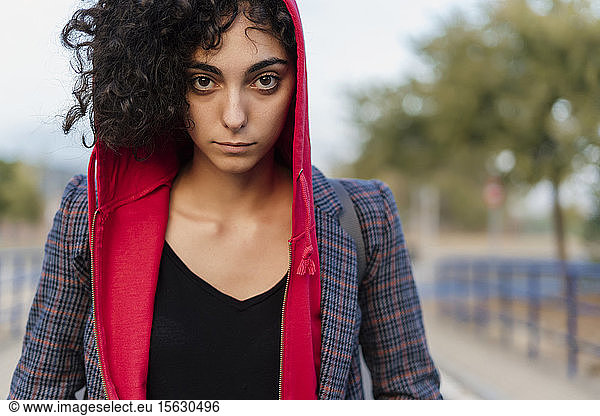 Portrait of young woman with curly hair wearing hooded jacket