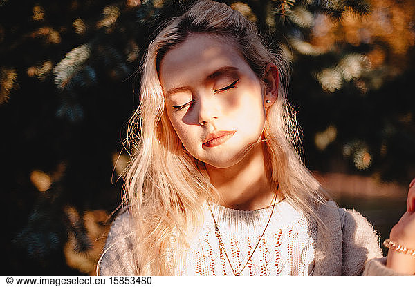 Portrait of young woman with eeditorial closed standing in front of sunlight