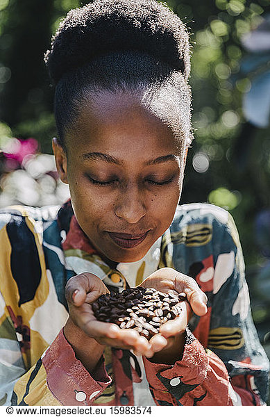 Portrait of young woman with eyes closed smelling roasted coffee beans