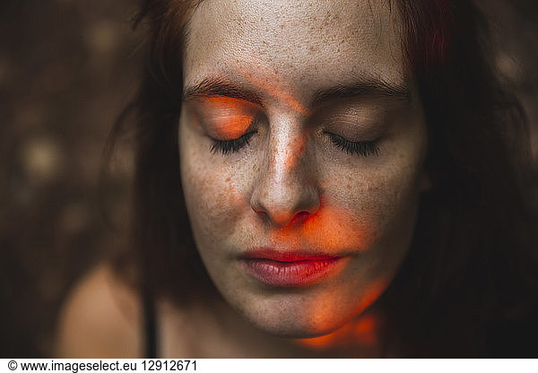 Portrait of young woman with freckles closing her eyes