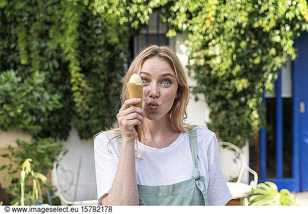 Portrait of young woman with ice cream cone pulling funny faces