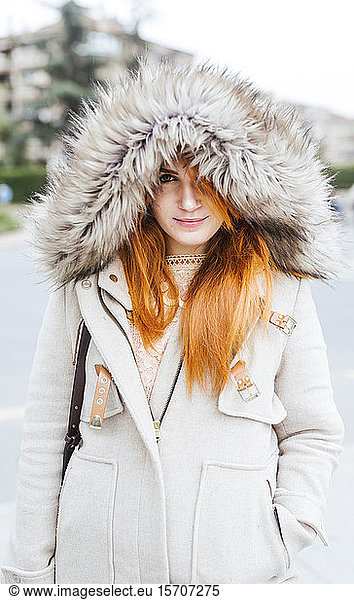 Portrait of young woman with orange dyed hair wearing hooded jacket in autumn