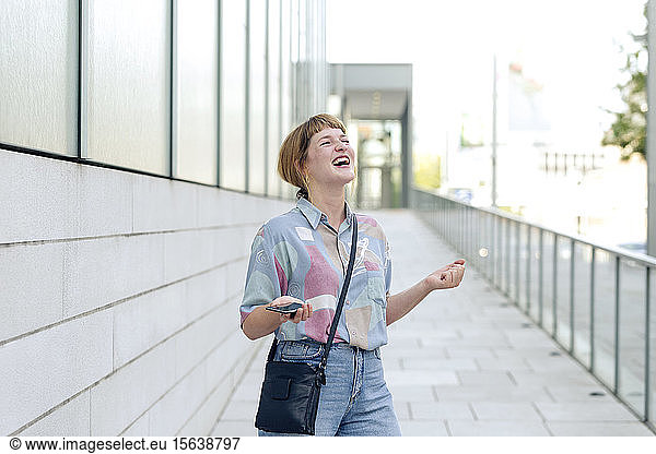 Portrait of young woman with smartphone freaking out