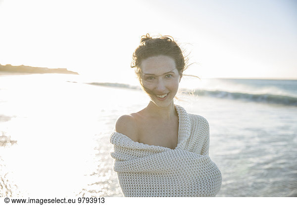 Portrait of young woman wrapped in blanket on beach